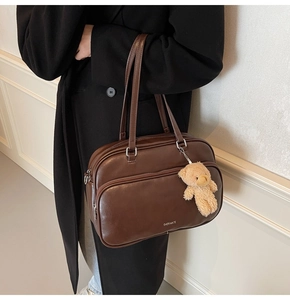 Detail of dark brown vintage pillow bag with silver zipper and plush bear charm