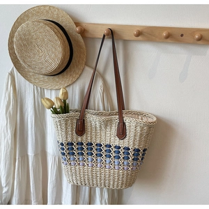 Détails d'un sac cabas en paille tressée avec motifs violets et anses en cuir robustes