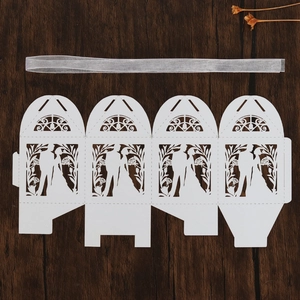 Flat lay of laser-cut white wedding favor box featuring bride and groom silhouettes