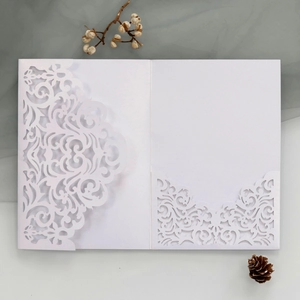 Detail of white laser-cut wedding invitation pocket with intricate floral hollow patterns