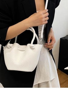 Minimalist white pebbled leather bucket bag with knotted handle and adjustable strap