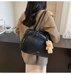 Detail of black large capacity shoulder bag with silver zipper and plush bear charm