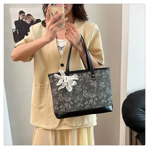 Detail of floral tote bag with embroidery, black handles and flower charm pendant