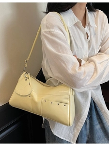 Minimalist pale yellow patent leather shoulder bag with heart charm and rivet details