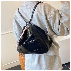 Detailed view of black crocodile pattern backpack with silver buckle and braided charm