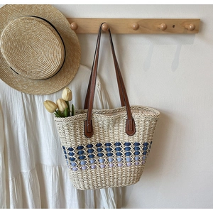 Détail du sac cabas en paille tressée avec motif dégradé bleu et anses en cuir