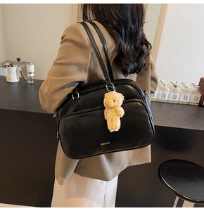 Detail of black leather Boston bag with white CHERIMATE lettering and a cute bear charm