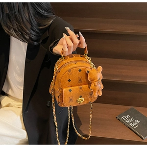 Detail eines Mini-Eimer-Rucksacks mit Bärenmuster, Goldkette und Bären-Anhänger