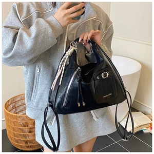 Detail of black crocodile texture hobo bag with silver zipper and woven pendant charm