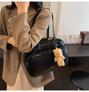 Detail of black leather Boston bag with plush bear charm and CHERIMATE branding text