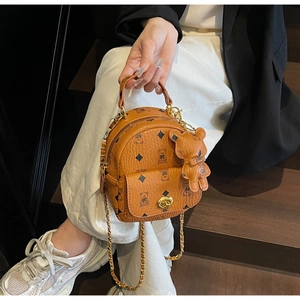Detail eines braunen Mini-Rucksacks mit Bärendruck, Goldkette und Bärenanhänger