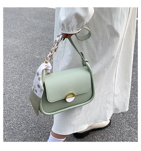 Détail du sac selle vert menthe avec chaîne entourée d'un foulard et boucle dorée