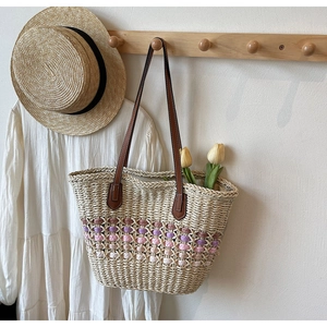 Détail du sac cabas en paille tissée avec motifs géométriques et anses en cuir brun
