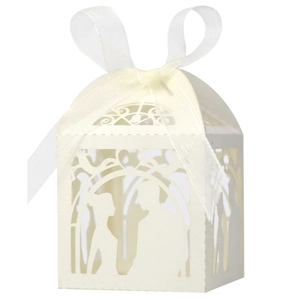 Detail of laser-cut white wedding favor box showing bride and groom silhouette with ribbon