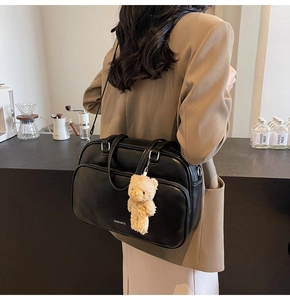 Close-up of black matte PU leather tote with brand logo and cute plush bear charm detail