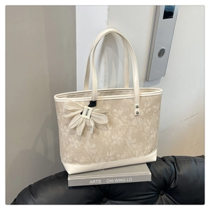 Close-up of floral beige tote bag with white leather trim and a 3D flower charm