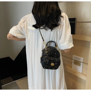 Detail eines schwarzen Mini-Monogramm-Rucksacks mit goldener Schließe und Kettenriemen