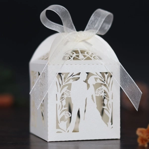 Macro shot of white laser-cut wedding favor box with pearl paper and sheer organza ribbon