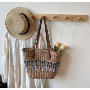 Détail d'un sac cabas en paille tissée avec anses en cuir marron et motif dégradé bleu