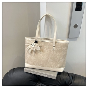 Detail of floral jacquard fabric on the beige tote bag with a white flower pendant