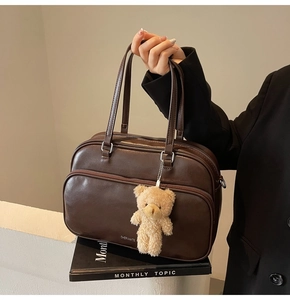 Detail of dark brown vintage Boston bag with plush bear charm and brand logo