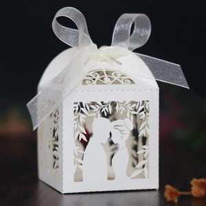 Detail of laser-cut wedding favor box in white pearlescent paper with ribbon bow