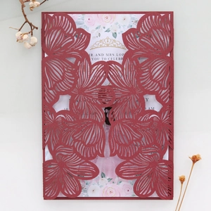 Detail of laser-cut burgundy invitation cover with floral printed inner card and dry flowers