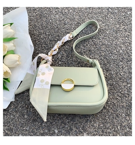 Détail du sac selle vert sauge avec fermoir doré et foulard en soie décoratif