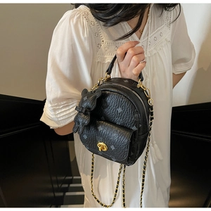 Detail eines schwarzen Mini-Rucksacks mit Goldschloss, Kette und Hasen-Anhänger