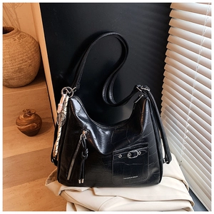 Detail of black crocodile texture tote bag with silver zipper and tassel accent