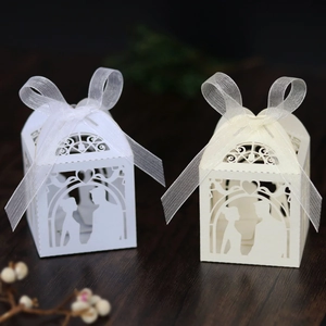 Detail of laser-cut wedding favor boxes with bride and groom silhouettes and ribbon bows