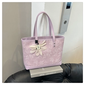Detail of lavender tote bag with floral embossing and a white flower charm on a book