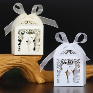 Detail of laser-cut wedding candy boxes with bride and groom silhouettes and ribbon bows