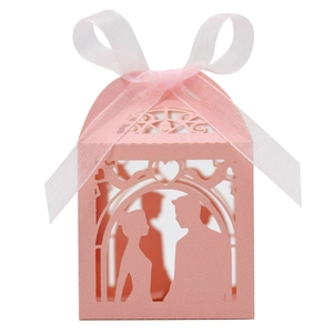 Detail view of pink laser-cut wedding favor box with romantic couple silhouette and ribbon bow