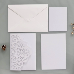 Macro shot of white laser cut floral wedding invitation with envelopes and inserts