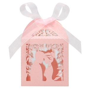 Detail of pink laser-cut wedding favor box with romantic silhouette and white ribbon bow