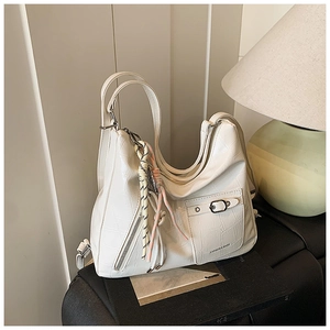 Detail of cream white tote bag featuring crocodile texture and woven strap charm