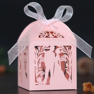 Detailed laser-cut pink wedding favor box with ribbon and romantic silhouette design
