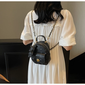 Nahaufnahme des schwarzen Mini-Rucksacks aus Leder mit Lorbeermuster und Bärenanhänger