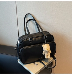 Detail of black leather boston bag with bear charm and CHERIMATE brand lettering