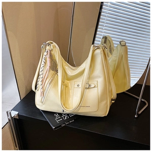 Detail of light yellow hobo bag with crocodile texture and woven rope charm