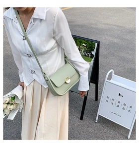 Détail du sac selle vert pistache avec boucle métallique et ruban de soie floral