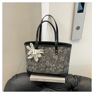 Detailed view of embroidery floral tote bag with a 3D flower charm and black trim