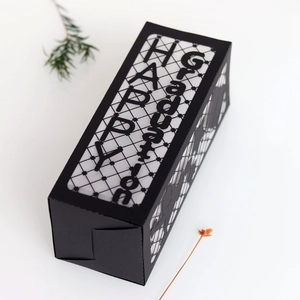 Detail of laser-cut HAPPY Graduation text and cap silhouette on black paper lantern box