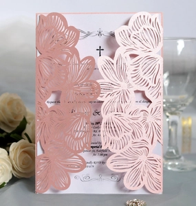 Macro detail of laser-cut floral pattern and religious cross on wedding invitation