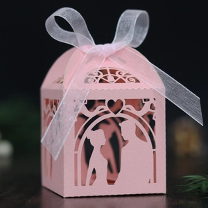Close-up of laser-cut pink wedding favor box with bride and groom silhouette and ribbon