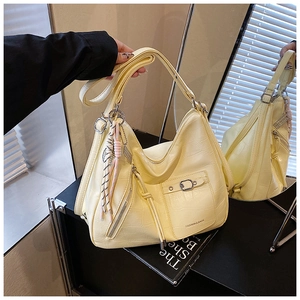 Macro view of cream crocodile-embossed hobo bag with braided tassel and metal clasp