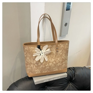 Close-up of floral tote bag with brown leather trim and decorative flower pendant
