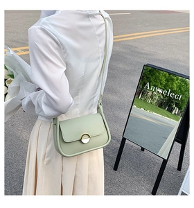 Photo de rue d'un sac besace en cuir vert menthe avec boucle dorée en gros plan