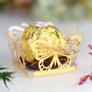Macro shot of laser-cut butterfly gold paper hollow chocolate holder for wedding party